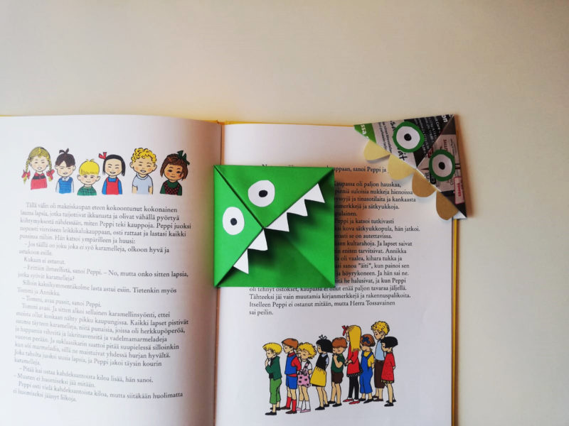 Vihreä hassu kirjamerkki kirjan aukeamalla.