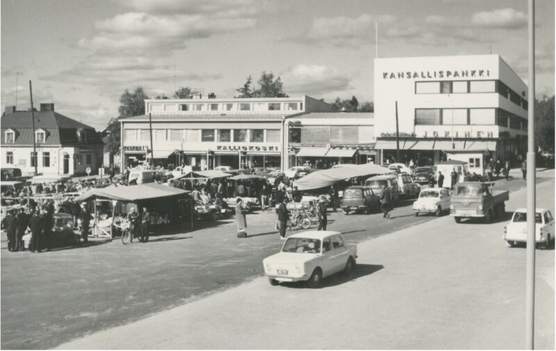Mustavalkoinen kuva julisteesta jossa autoja ja kerrostaloja